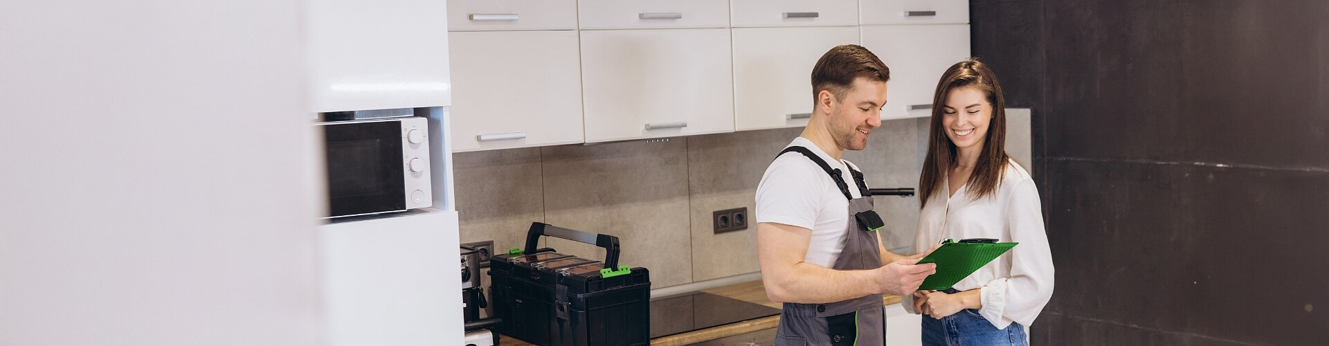 Młoda kobieta stoi w kuchni i omawia szczegóły usługi z fachowcem
