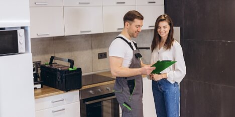 Młoda kobieta stoi w kuchni i omawia szczegóły usługi z fachowcem