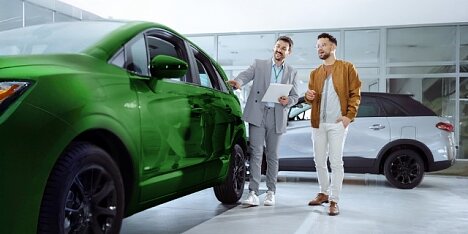 Mężczyzna ogląda w salonie samochodowym nowe, zielone auto