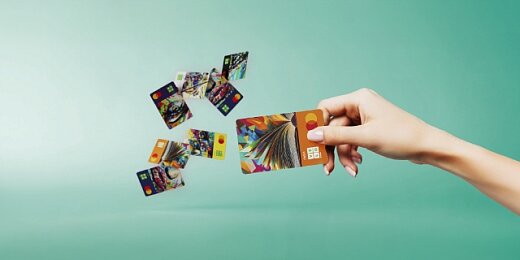 Grafika przedstawiająca kobiecą dłoń rozrzucającą karty płatnicze z nowymi wizerunkami VeloBank