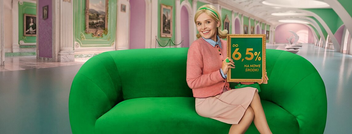 Pani siedzi na zielonej kanapie i trzyma tabliczkę z napisem ''do 6,5%'''