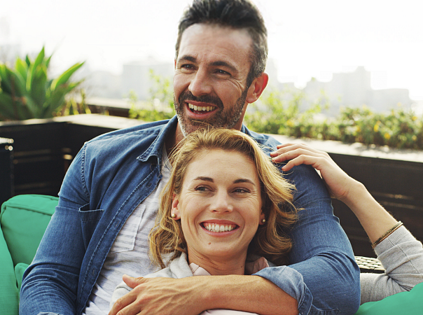 Zrelaksowana para odpoczywa na swoim patio z panoramą miasta w tle