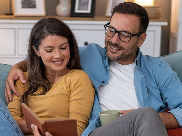 Para relaksuje się w salonie czytając wspólnie książkę