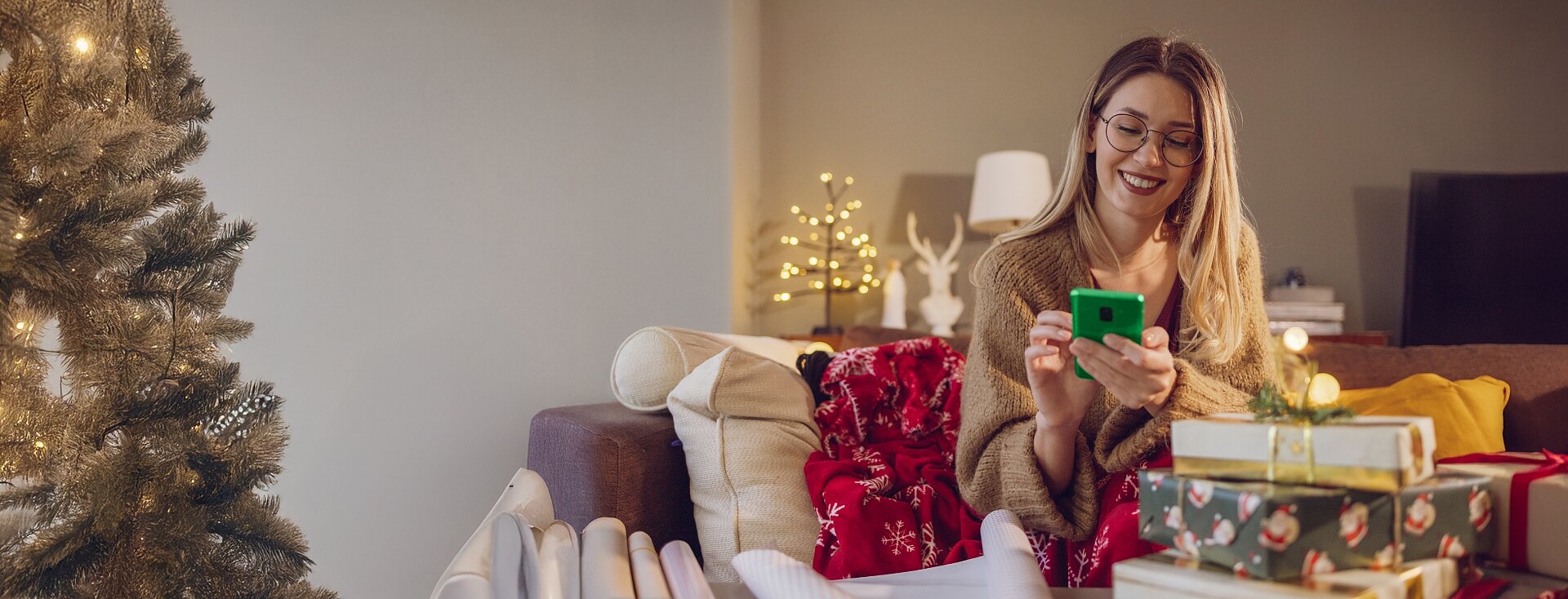 Dziewczyna sprawdza informacje na smartfonie w świątecznej scenerii.