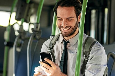 Mężczyzna w autobusie kupuje bilet przy użyciu aplikacji na telefonie.