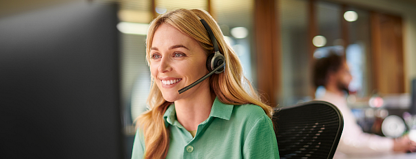 Uśmiechnięta kobieta ze słuchawkami pracująca w Call Center.