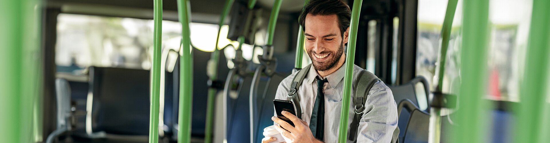 Mężczyzna w autobusie kupuje bilet przy użyciu aplikacji na telefonie.
