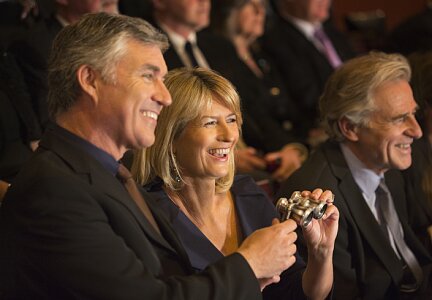 Roześmiana para w średnim wieku oklaskuje występ teatralny