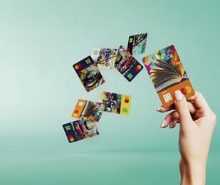 Grafika przedstawiająca kobiecą dłoń rozrzucającą karty płatnicze z nowymi wizerunkami VeloBank