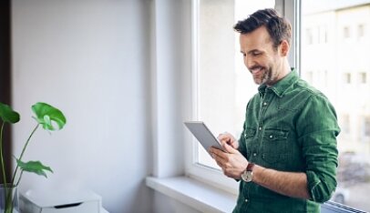 Zadowolony mężczyzna prowadzący swój biznes korzysta na tablecie z oferty VeloBanku dla mikrofirm