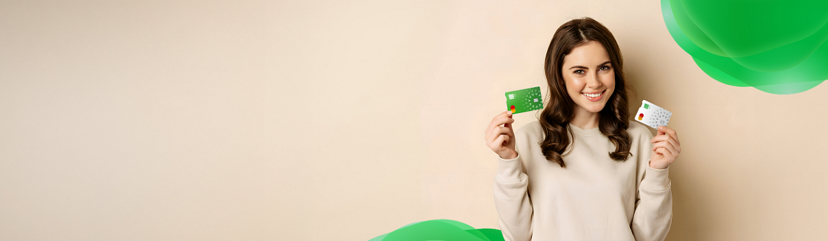 Uśmiechnięta dziewczyna trzyma karty - debetową i kredytową.