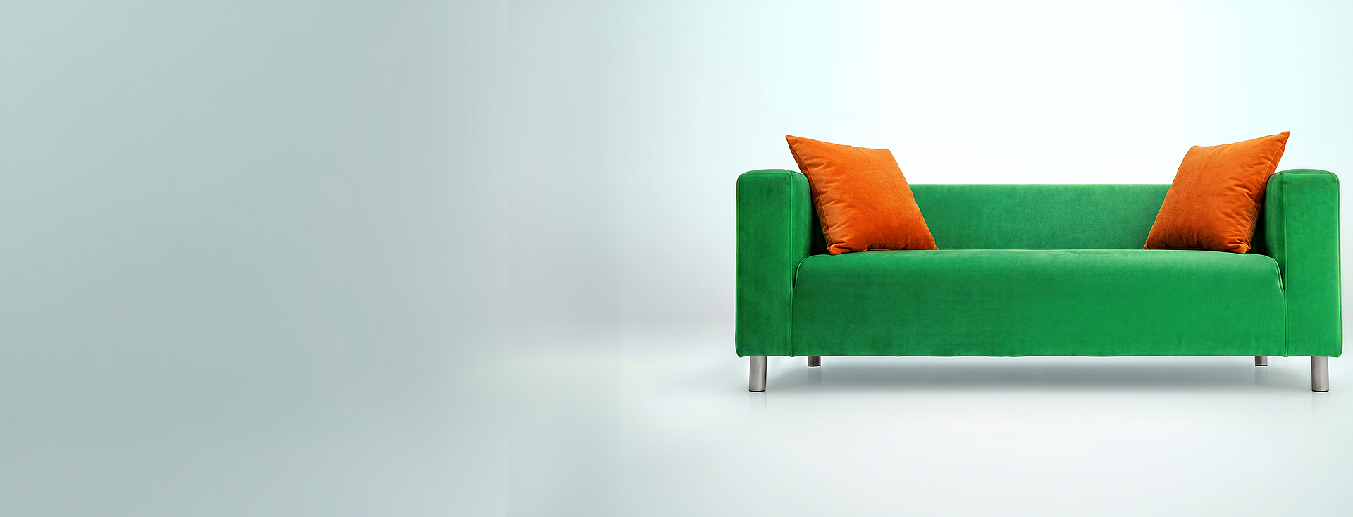Zielona sofa z pomarańczowymi poduszkami symbolizująca wygodę w ofercie ubezpieczeniowej VeloBank