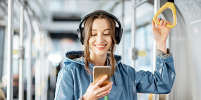 Dziewczyna w autobusie korzysta ze smartfona i kupuje bilet komunikacji miejskiej w apllikacji.