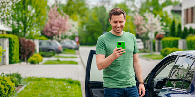 Mężczyzna stoi przy samochodzie i korzysta z opcji opłaty za parking w aplikacji.