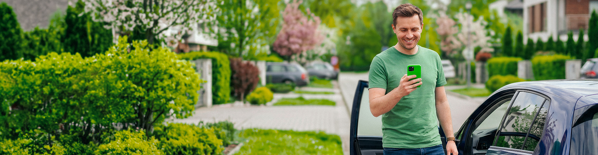Mężczyzna stoi przy samochodzie i korzysta z opcji opłaty za parking w aplikacji.