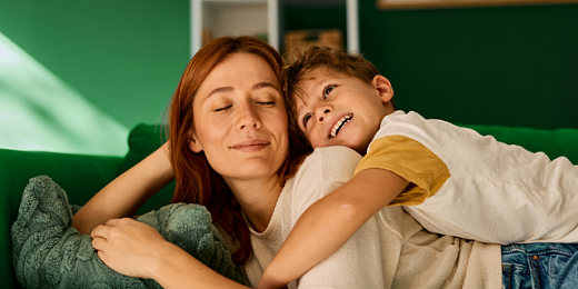Spokojna kobieta odpoczywa ze swoim uśmiechniętym synem na zielonej sofie