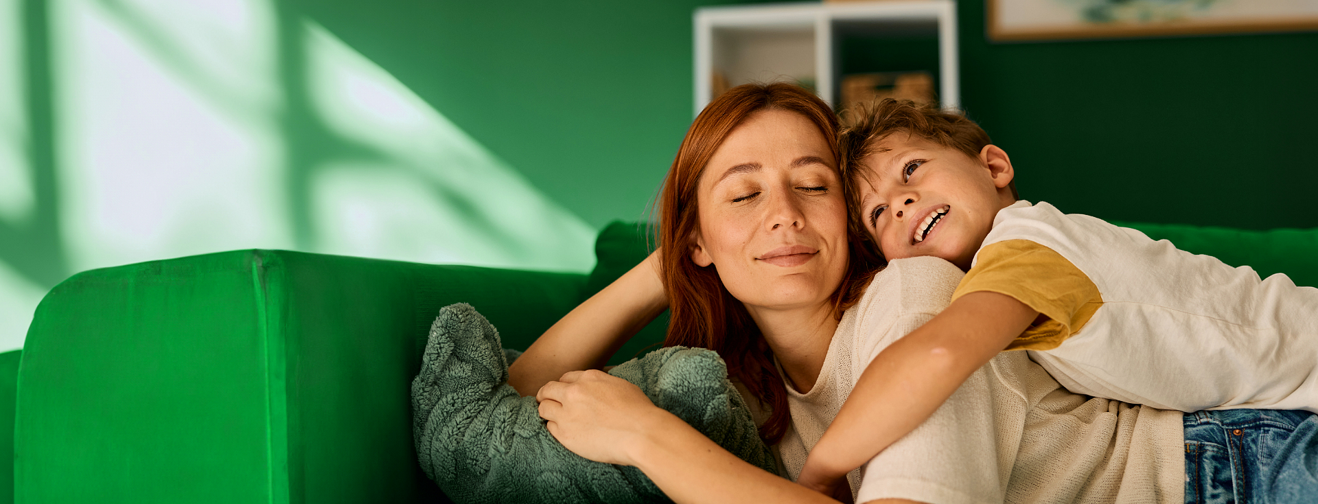 Spokojna kobieta odpoczywa ze swoim uśmiechniętym synem na zielonej sofie