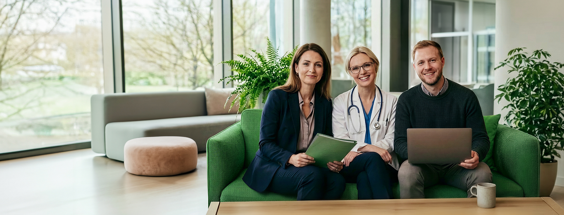 Trójka szczęśliwych ludzi w służbowych strojach siedzi na kanapie w rozświetlonym, nowoczesnym domu