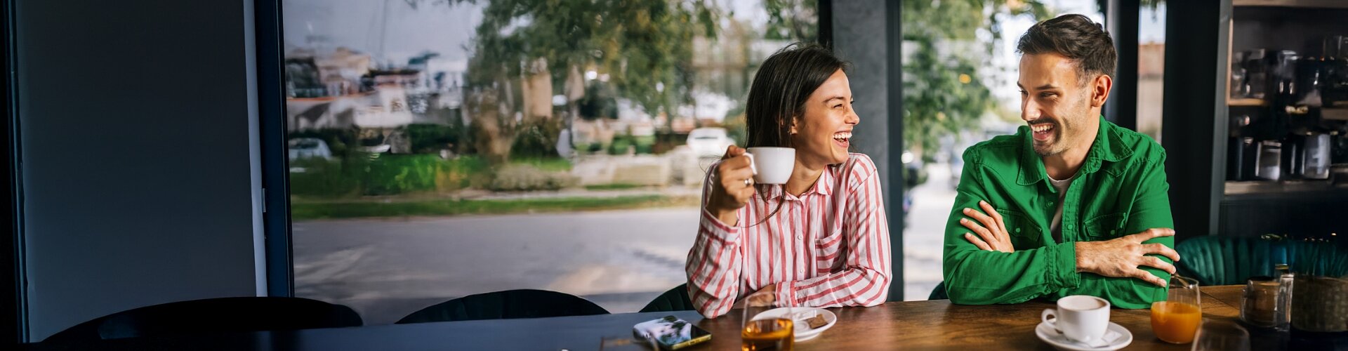 Roześmiana para rozmawia w kawiarni po skorzystaniu z Promocji VeloPolecenie