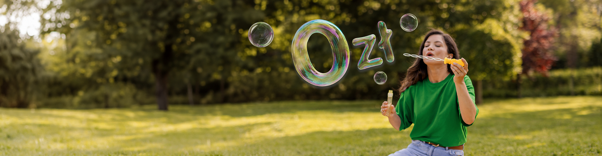 Młoda kobieta w zielonym swetrze wypuszcza bańki układające się w kształt 0 zł