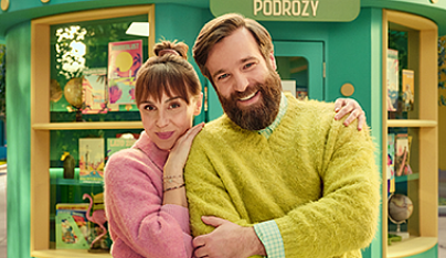 Kolorowo ubrana para uśmiecha się na ulicy otoczona symbolami przedstawiającymi zalety pożyczki gotówkowej w VeloBank