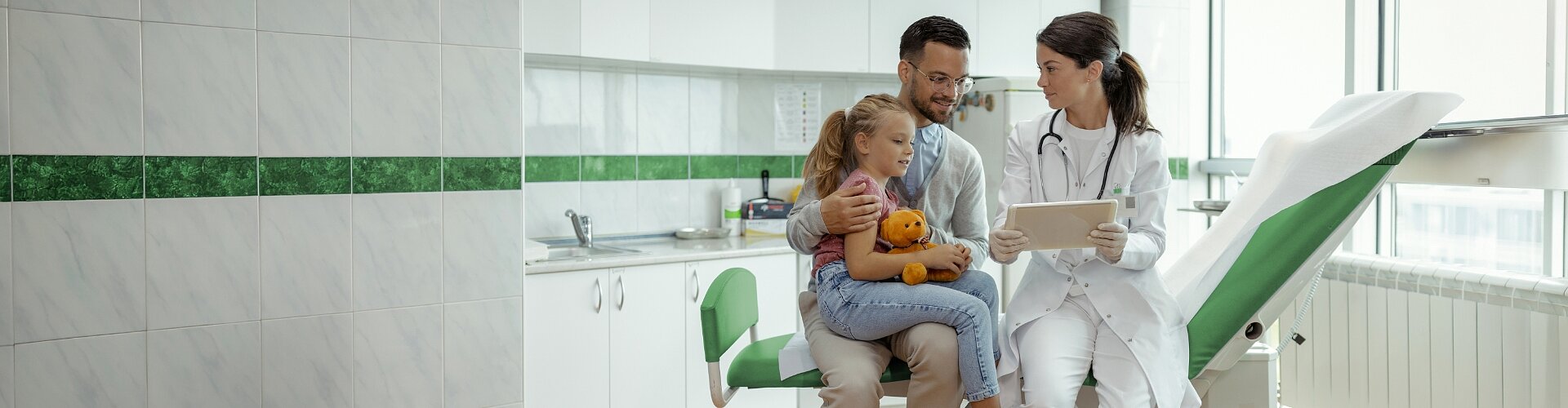 Tata i jego córka w gabinecie lekarskim, gdzie doktor prezentuje im wyniki badań w ramach Pakietu Medycznego