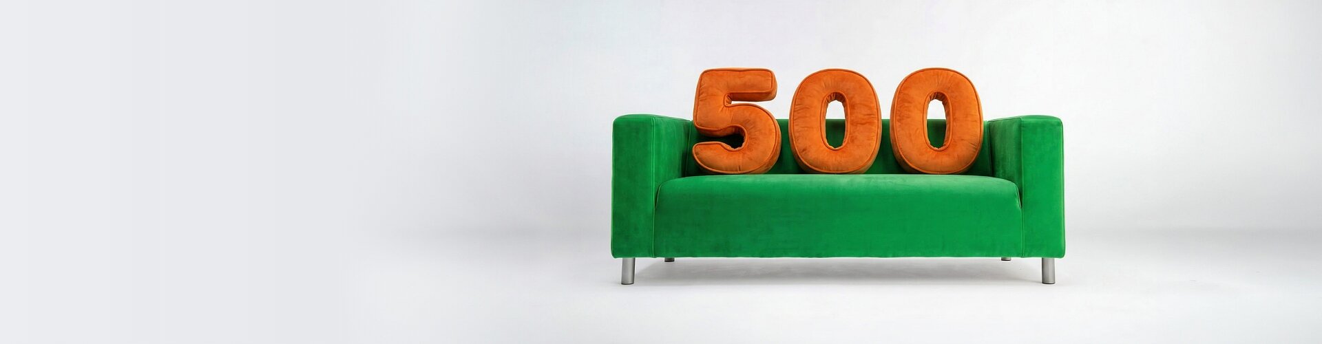 Zielona sofa z pomarańczowymi poduszkami symbolizująca wygodę w ofercie ubezpieczeniowej VeloBank